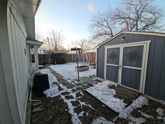 snowy yard featuring a storage unit