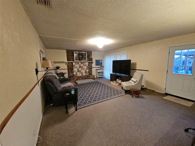 living room featuring carpet floors, a stone fireplace, and a textured ceiling