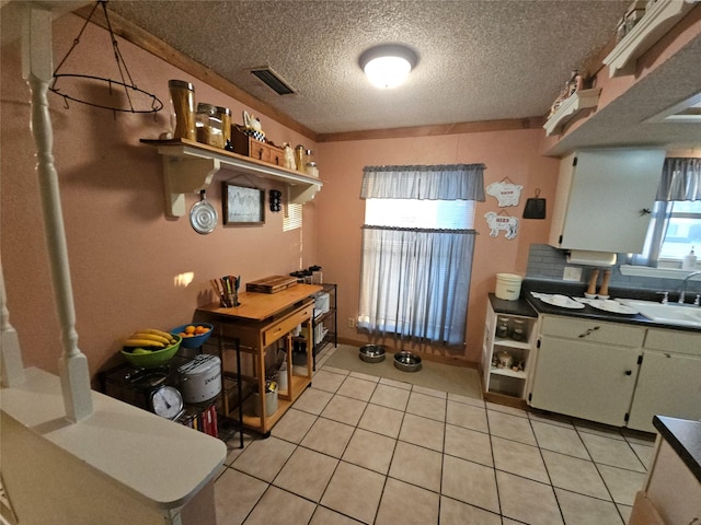 kitchen with sink, light tile patterned flooring, a textured ceiling, and decorative backsplash