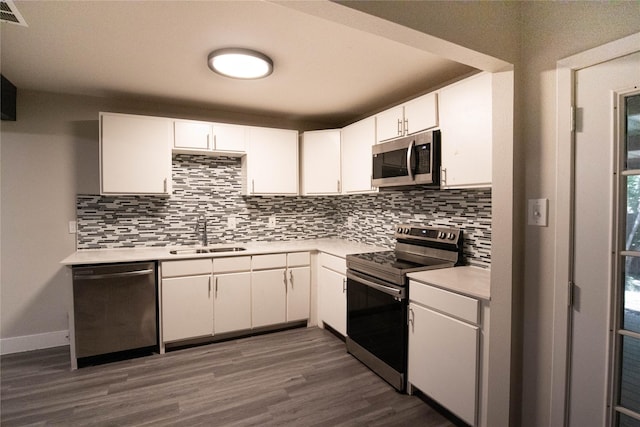 kitchen with sink, white cabinets, dark wood-type flooring, decorative backsplash, and stainless steel appliances