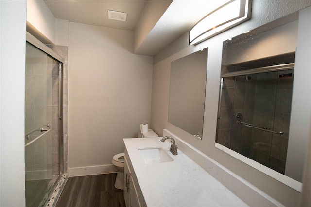 bathroom with wood-type flooring, toilet, walk in shower, and vanity