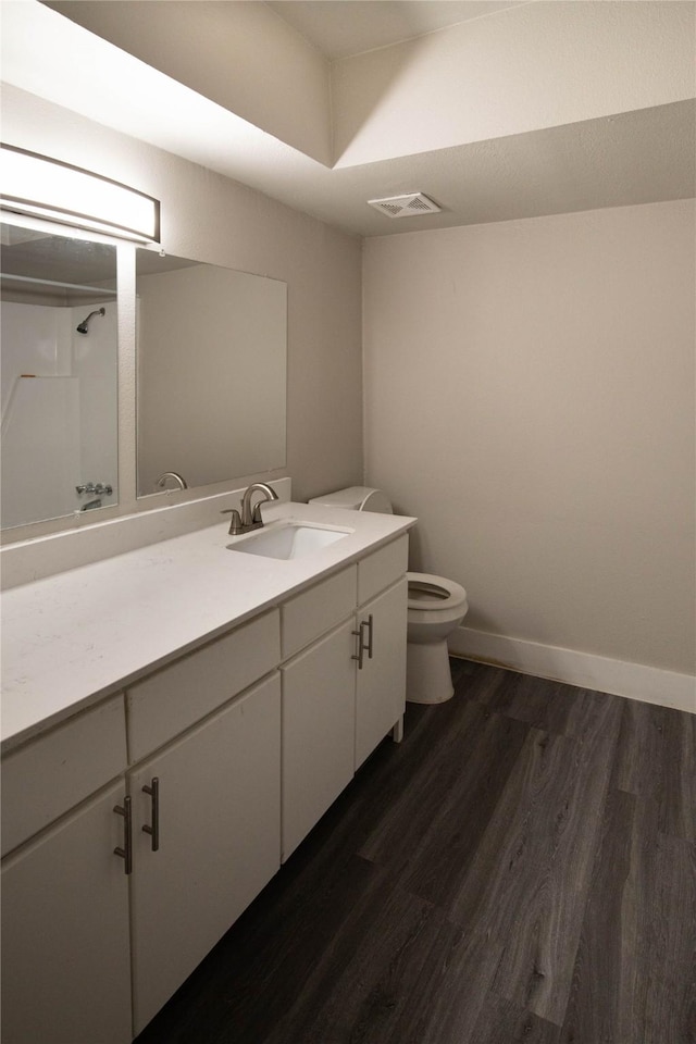 bathroom featuring wood-type flooring, walk in shower, vanity, and toilet