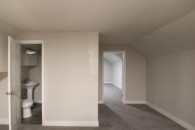 additional living space featuring dark colored carpet, an AC wall unit, and vaulted ceiling