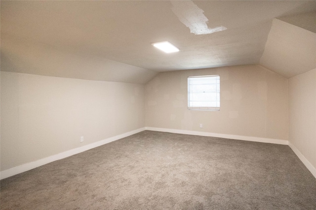 additional living space with dark colored carpet and lofted ceiling