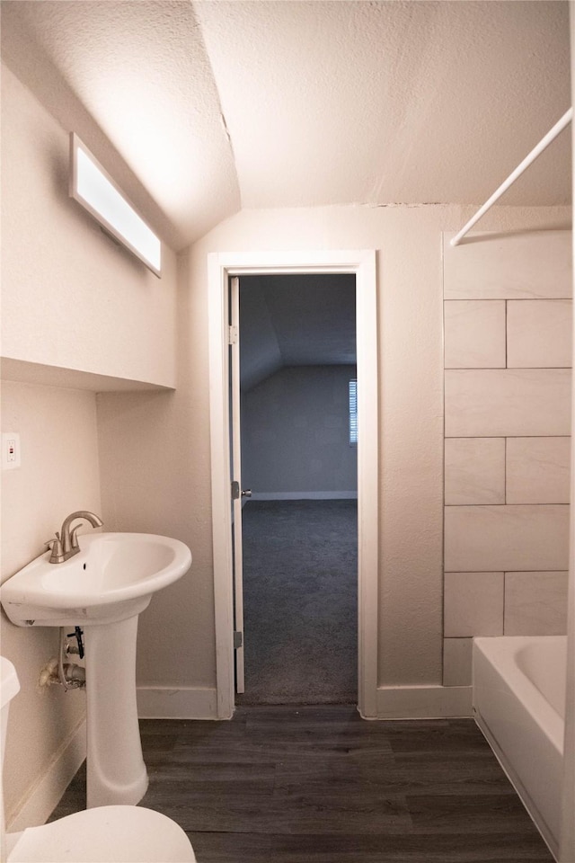 bathroom with hardwood / wood-style flooring, a textured ceiling, toilet, and vaulted ceiling