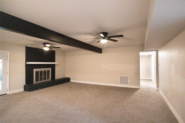 unfurnished living room featuring light carpet, beam ceiling, a fireplace, and ceiling fan