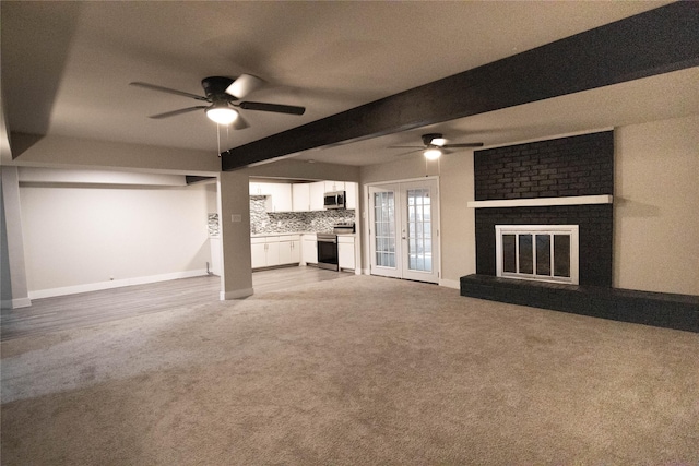 unfurnished living room with ceiling fan, french doors, a brick fireplace, and beam ceiling