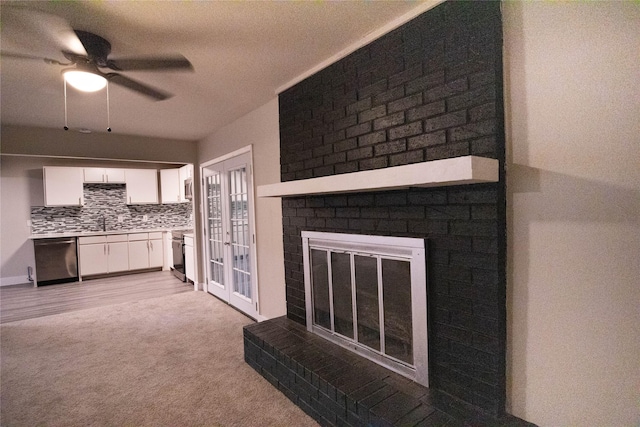 unfurnished living room featuring sink, ceiling fan, light colored carpet, and a fireplace