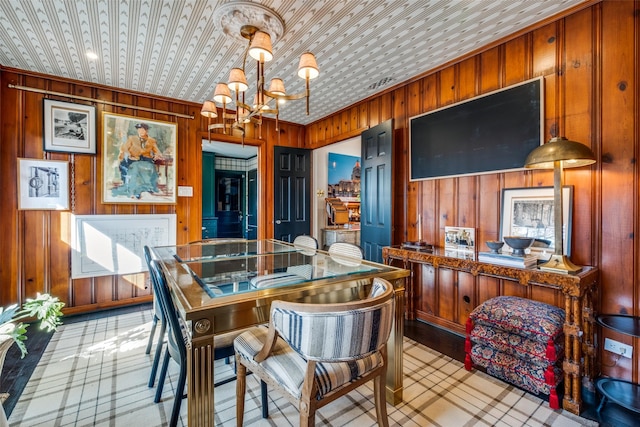 dining room with wood walls and a notable chandelier