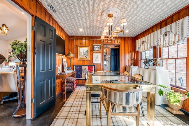 dining room featuring wood walls and a chandelier