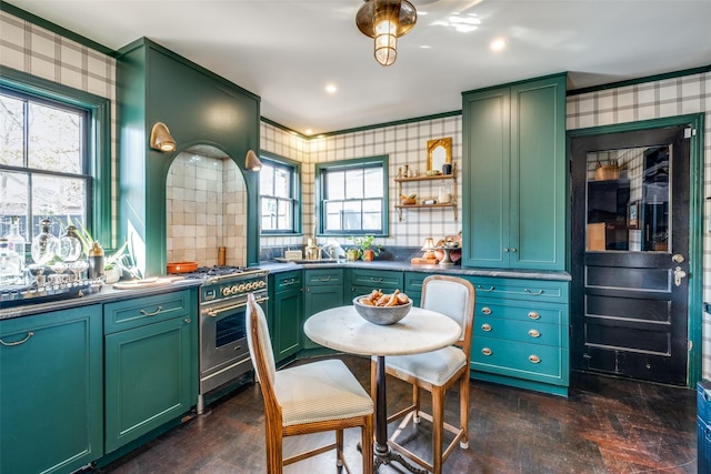 kitchen with backsplash, green cabinets, and stainless steel range