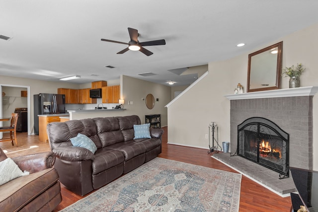 living room featuring ceiling fan, a fireplace, and light wood-type flooring