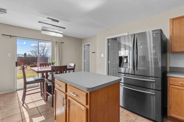 kitchen with tasteful backsplash, stainless steel refrigerator with ice dispenser, a center island, and light tile patterned floors