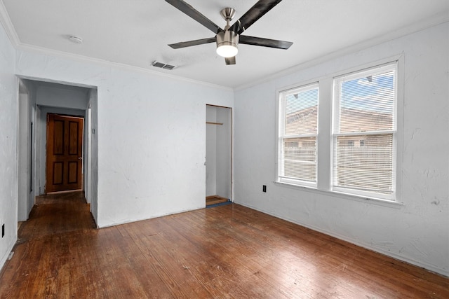 empty room with crown molding, dark wood-type flooring, and ceiling fan