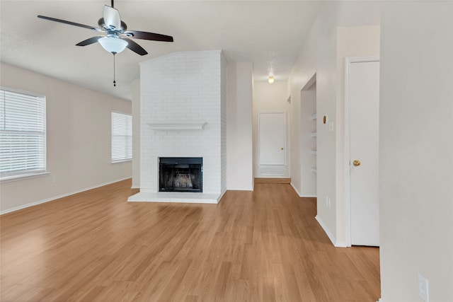 unfurnished living room featuring ceiling fan, light hardwood / wood-style flooring, a fireplace, and lofted ceiling