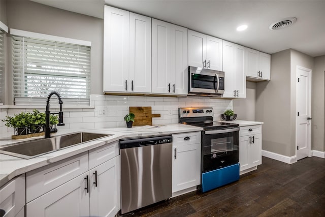 kitchen with sink, stainless steel appliances, white cabinetry, and dark wood-type flooring