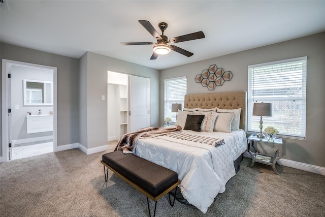 carpeted bedroom featuring ceiling fan, multiple windows, and ensuite bath