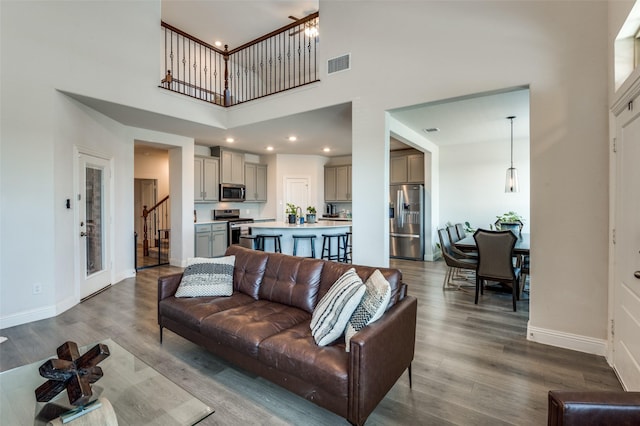 living room with wood-type flooring and a towering ceiling