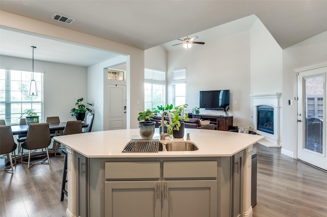 kitchen featuring gray cabinetry, sink, dark wood-type flooring, pendant lighting, and a center island with sink