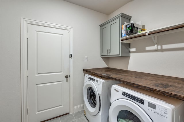 clothes washing area featuring light tile patterned floors, cabinets, and washer and clothes dryer