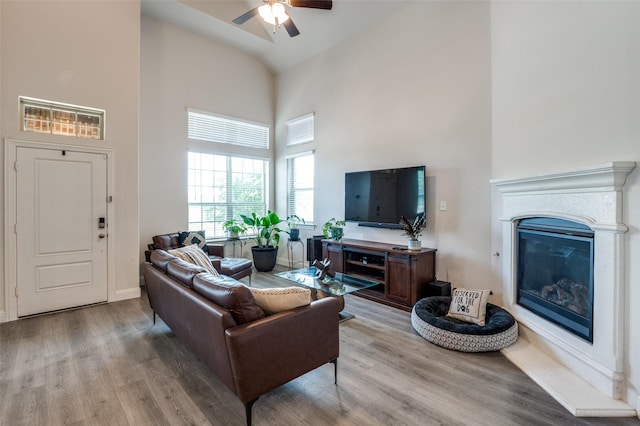 living room with light hardwood / wood-style flooring, a high ceiling, and ceiling fan