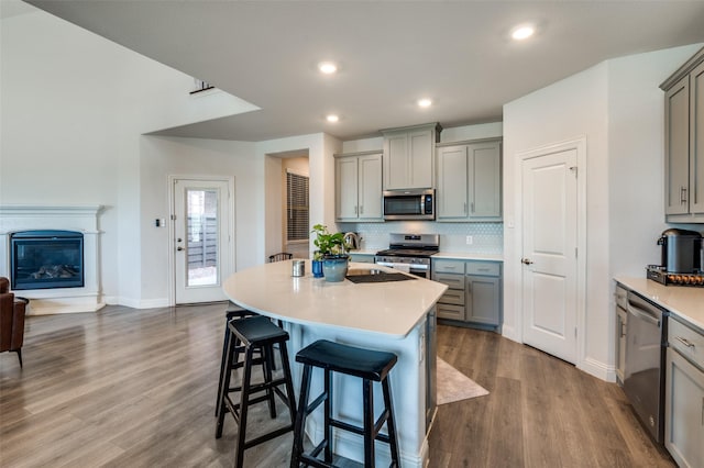 kitchen featuring gray cabinets, a center island, a breakfast bar area, and appliances with stainless steel finishes