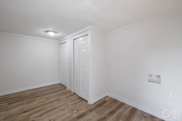 unfurnished bedroom with wood-type flooring, a closet, and crown molding