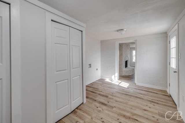 hallway with brick wall and light wood-type flooring