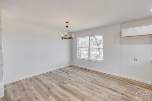 spare room with an inviting chandelier and light hardwood / wood-style floors