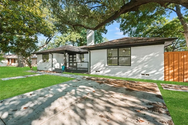 rear view of house featuring a lawn and a patio