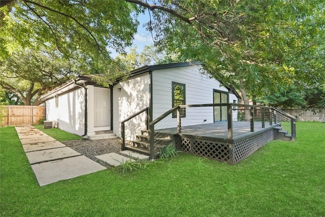 rear view of house with a wooden deck and a lawn