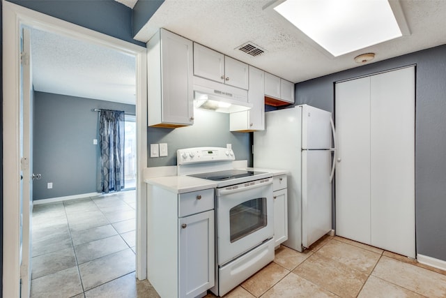 kitchen with light tile patterned floors, white appliances, white cabinets, and a textured ceiling