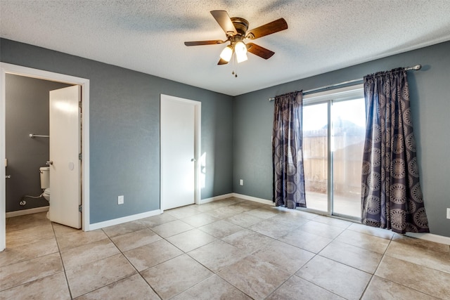 unfurnished bedroom featuring a textured ceiling, ensuite bathroom, light tile patterned floors, and ceiling fan