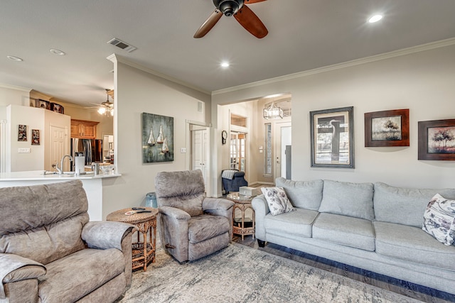 living room featuring ceiling fan, ornamental molding, and sink