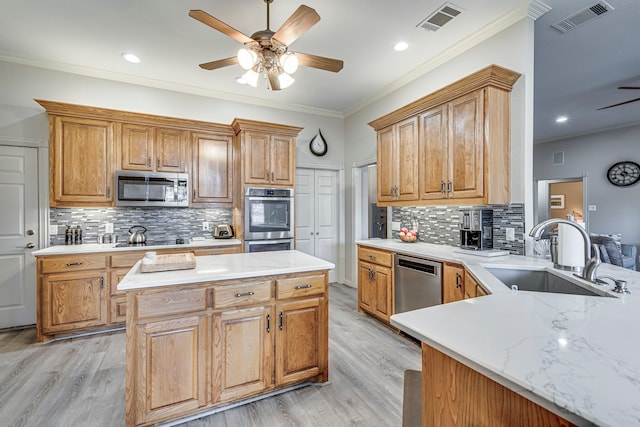 kitchen featuring sink, crown molding, appliances with stainless steel finishes, kitchen peninsula, and light hardwood / wood-style floors