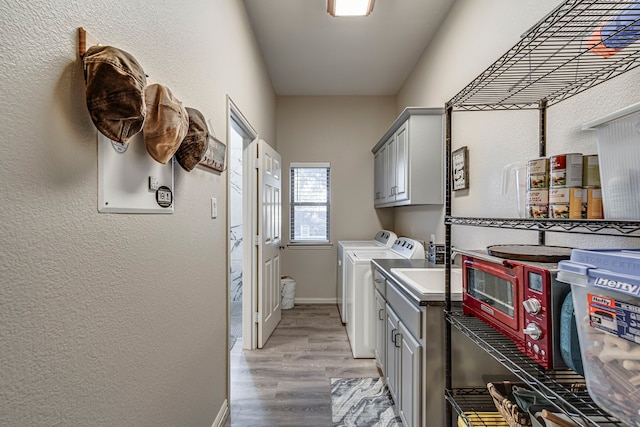 laundry room featuring washer and clothes dryer, light hardwood / wood-style flooring, and cabinets