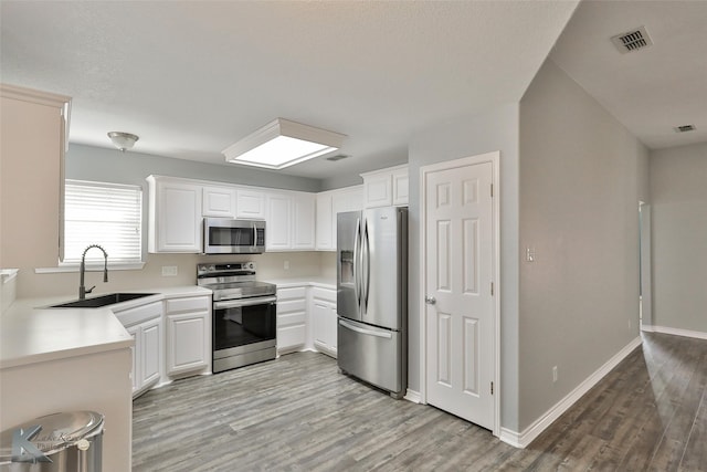 kitchen with sink, white cabinetry, light hardwood / wood-style flooring, and stainless steel appliances