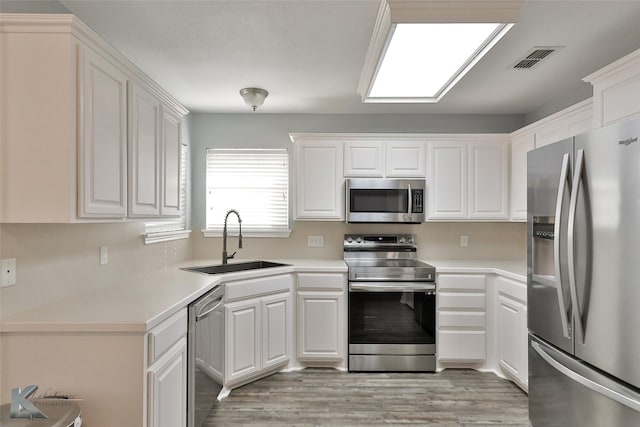 kitchen featuring light hardwood / wood-style floors, sink, white cabinetry, and appliances with stainless steel finishes