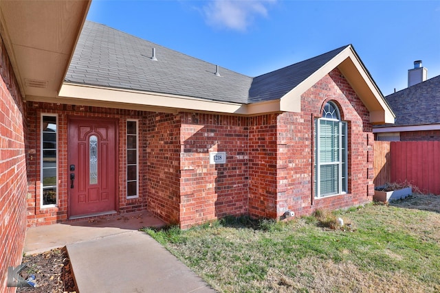 view of exterior entry with a patio area and a lawn