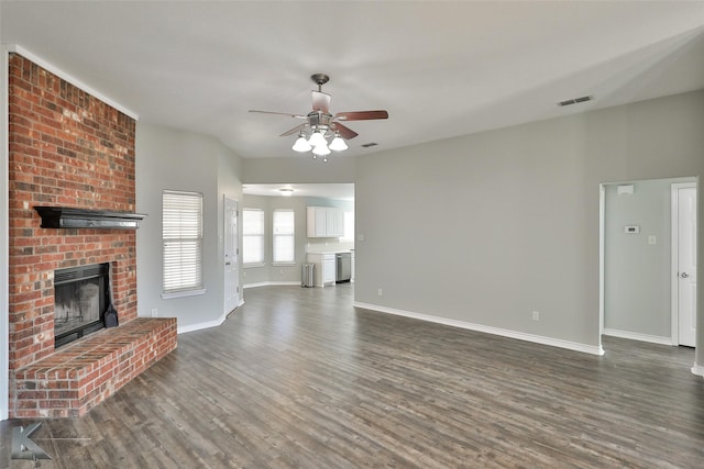 unfurnished living room featuring ceiling fan, a brick fireplace, and dark hardwood / wood-style floors