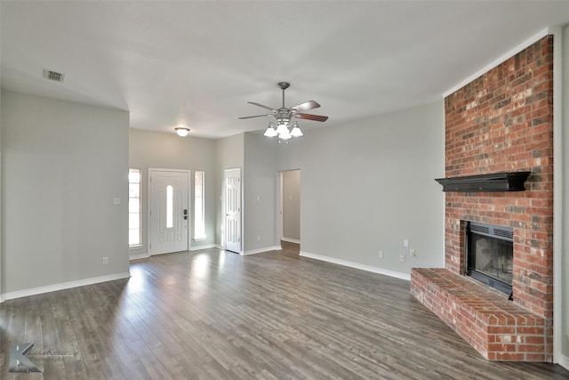 unfurnished living room with ceiling fan, a brick fireplace, and dark hardwood / wood-style flooring