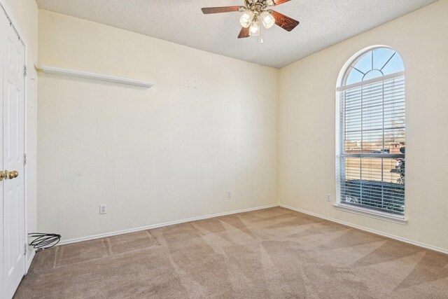 unfurnished room with ceiling fan, light carpet, and a textured ceiling