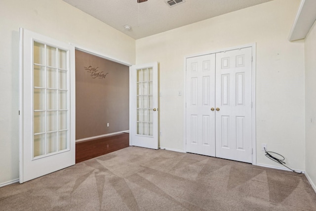 unfurnished bedroom with light carpet, a closet, and a textured ceiling