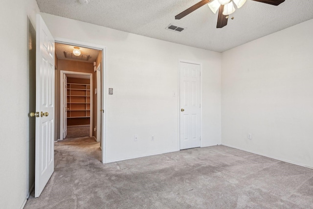 unfurnished bedroom with light colored carpet, a textured ceiling, and ceiling fan