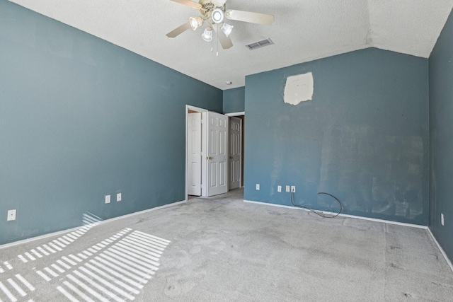 unfurnished bedroom featuring lofted ceiling, light colored carpet, a textured ceiling, and ceiling fan