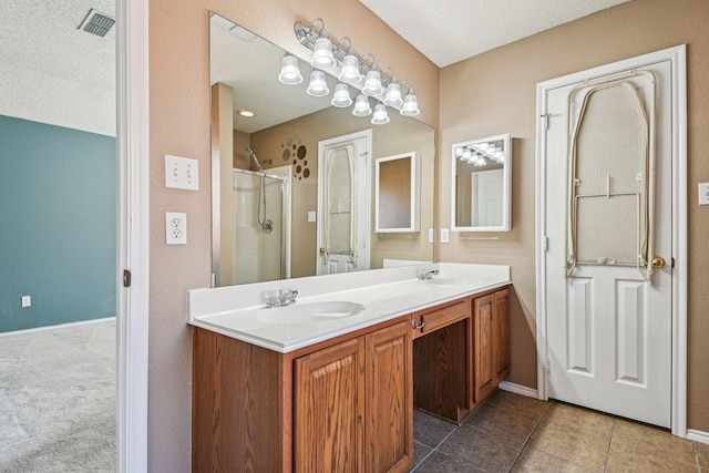 bathroom featuring vanity, tile patterned flooring, a shower with door, and a textured ceiling