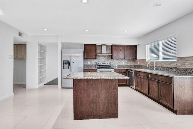 kitchen featuring sink, a center island, light stone counters, stainless steel appliances, and wall chimney exhaust hood