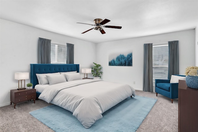 bedroom featuring ceiling fan, light carpet, and multiple windows