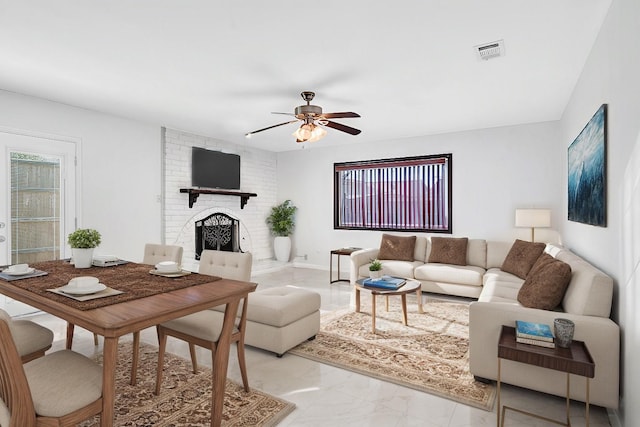 living room with ceiling fan and a brick fireplace