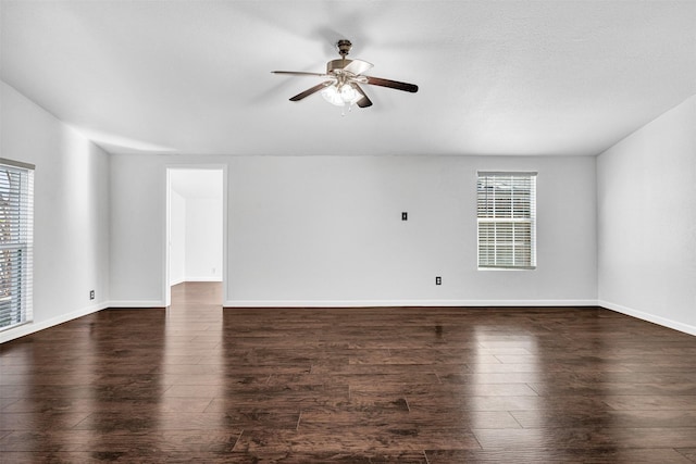 empty room with plenty of natural light, dark wood-type flooring, and ceiling fan